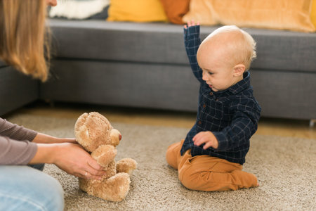 Happy toddler boy playing with her teddy bear at house - childhood and child development stages conceptの写真素材