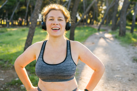 Fat woman and sports. Girl doing exercise for weight loss in the fresh air and laughing in camera after training. Copy space and empty space for text or advertisingの写真素材