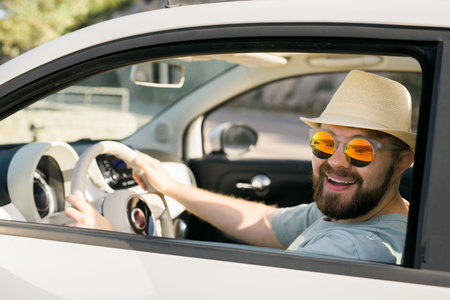 Happy man sitting in white convertible car with beautiful view and having fun - travel summer vacation and rental car conceptの写真素材