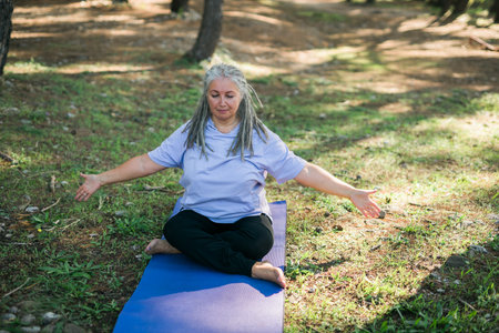 Mature old woman with dreadlocks practicing yoga and tai chi outdoors - wellbeing and wellnessの写真素材