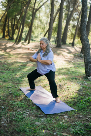 Mature old woman with dreadlocks practicing yoga and tai chi outdoors - wellbeing and wellnessの写真素材