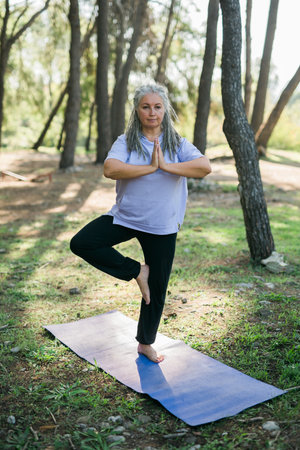 Mature old woman with dreadlocks practicing yoga and tai chi outdoors - wellbeing and wellnessの写真素材