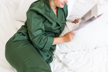 Close up woman wears pajama reads magazine in living room. Homewear, sleepwear, shopping and saleの写真素材
