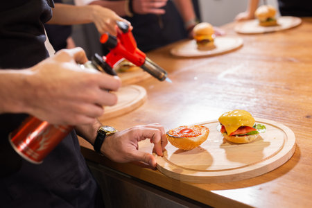 Preparing delicious burgers. Chef cooking meat burgers with beef, cheese and vegetables. Close-upの写真素材