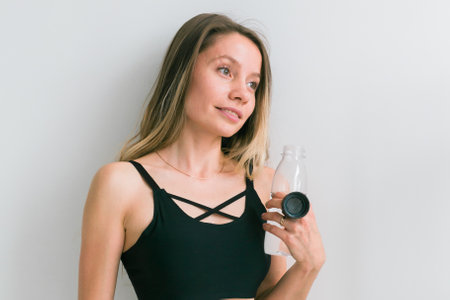 Sporty young woman drinking water after training. Active lifestyle and wellness