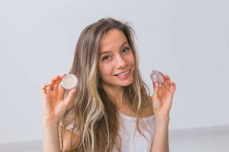 Portrait of beautiful young woman keeps makeup mineral powder for face and eyeshadows - make-up...