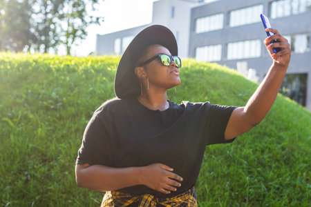 Attractive African woman taking selfie on the street wearing glasses - millennial and generation z...