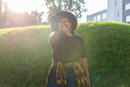Close up portrait of happy african american young woman browsing social networks in city -...
