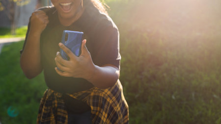 Close up portrait of happy african american young woman browsing social networks in city - generation z and urban conceptの写真素材