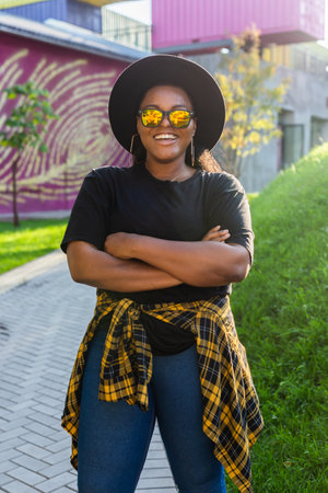 African american woman in an urban city area. Smiling generation z or millennial hipster girl posing outdoor backlit with sunlight portraitの写真素材