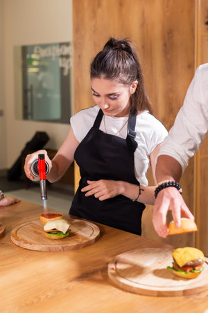 Preparing delicious burgers. Chef cooking meat burgers with beef, cheese and vegetables. Close-upの写真素材