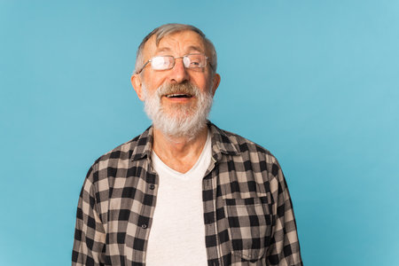 Portrait retired old man with white hair and beard laughter excited over blue color background