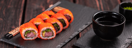 Banner California sushi roll with eel, cucumber and tobiko caviar served on black board close-up - Japanese foodの写真素材