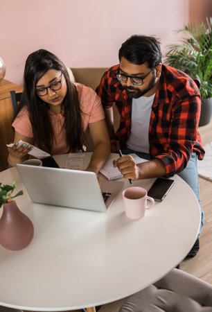 Serious wife and husband planning budget, checking finances, focused young woman using online...