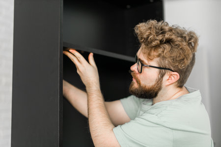 Portrait of man assembling furniture. Do it yourself furniture assembly at homeの写真素材