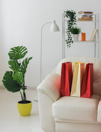Colorful shopping bags on sofa in living room - shopping addiction and online sale conceptの写真素材