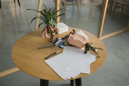 Table with business papers decorated with houseplants guzmania on desk. Exotic potted houseplants.