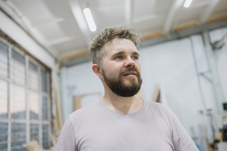 Portrait of gorgeous cute handsome man with beard and curly hair looking up with inspired dreamy facial expressionの写真素材