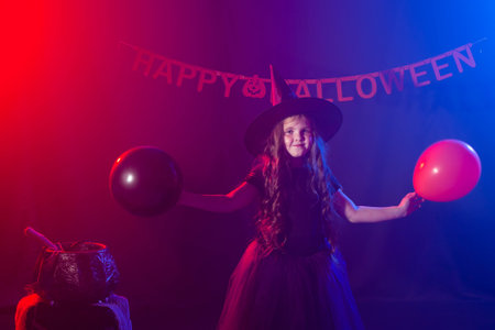 Little girl holds broom on Halloween holiday. Kid girl wear witch costume. Fantasy, fairy tale and masquerade concept.の写真素材