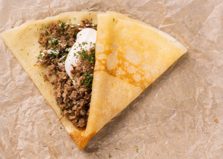 Pancakes stuffed with Bolognese filling minced beef pepper garlic and with bechamel sauce close-up top view. Crepe is dish french cuisine top viewの写真素材