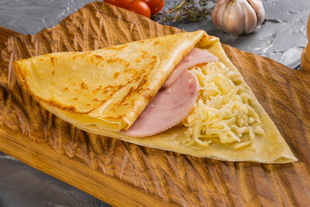 French crepe pancakes stuffed ham and cheese on cutting board close-up top viewの写真素材