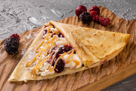 Pancake or crepe with cottage cheese and berries and sweet sauce close-up top view - dessertの写真素材