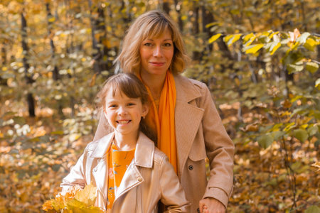 Beautiful lifestyle autumn photo mother and child walks evening in the park, warm sunlight.の写真素材