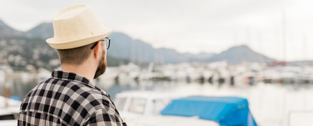 Banner rear view millennial man wearing hat with yachts and marina background with copy space and empty place for advertisingの写真素材