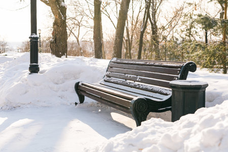 Bench in park with snow in winter season. City and town street conceptの写真素材