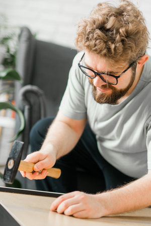Bearded millennial man assemble his bookcase. He uses tools for furniture. Furniture for the interior room or apartmentsの写真素材