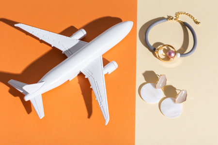 Modern minimalist handmade jewelry on orange and beige. Air plane toy for delivery and parcels on gift concept. Bracelets and earrings. Deliver handmade jewellery and accessoriesの写真素材