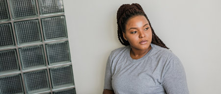 Beautiful African American woman with dreadlocks relaxing at home wearing gray t-shirt. Banner with...