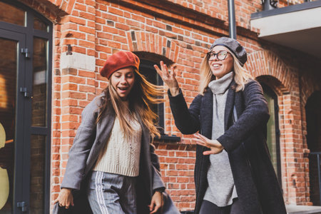 Millennial young women having fun and dance on city street. Female funny friends enjoying autumn day around the city.の写真素材