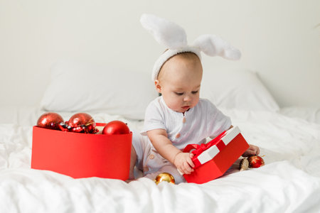 Adorable baby boy playing with Christmas baubles and new year gift. Winter holidays celebration and festive conceptの写真素材