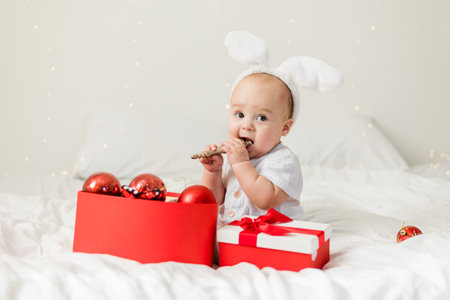 Christmas Baby Child holding christmas bauble near Present Gift Box over Holiday Lights backgroundの写真素材