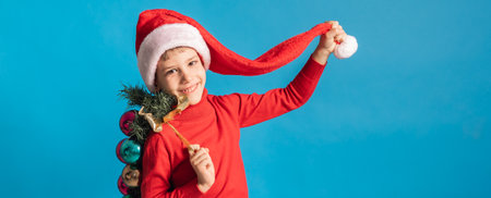 Banner cheerful child in santa hat hold christmas decorative balls on blue background, Xmas and...