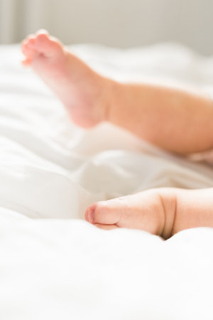 New born baby feet on white blanket on bedroom top view. Child and innocenceの写真素材