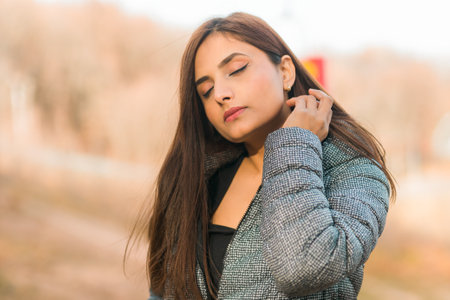 Close up portrait of pretty indian young woman enjoying warm autumn sunny day vacation outdoors copy space mockup. Generation z and gen z concept. Fall Seasonの写真素材