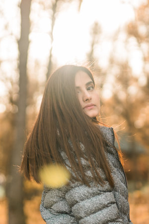 Close up portrait of pretty indian young woman enjoying warm autumn sunny day vacation outdoors. Generation z and gen z concept. Fall Seasonの写真素材
