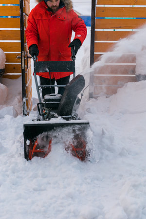 A man clear snow from backyard with snow blower. Winter season and snow blower equipment close-upの写真素材
