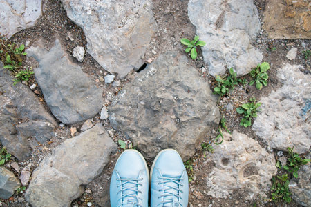 Womens legs in blue shoes on the stone pavement, top view. Photo pov. Copy space and empty place for textの写真素材