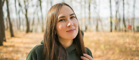 Banner millennial smiling woman walking outdoors in autumn nature with empty place for advertising...