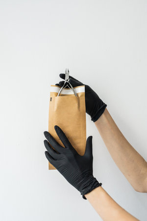 Woman manicure master or nail care beautician holding a manicure scissors on white wall. Cuticle...