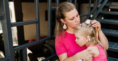 Mother holds and have fun her child with hearing aids and cochlear implants summer outdoor . Deaf and health concept. Diversity and inclusion. Copy space bannerの写真素材