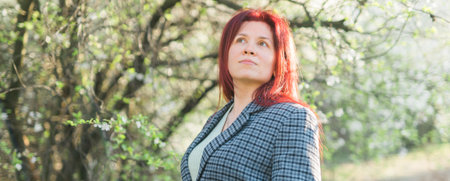 Banner beautiful happy millennial woman enjoying smell in a flowering spring garden. Blooming tree time. Copy space and empty place for advertising textの写真素材