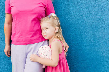 Blonde little girl with cochlear implant playing with her mother outdoor. Hear impairment deaf and health concept. Diversity and inclusion. Copy spaceの写真素材