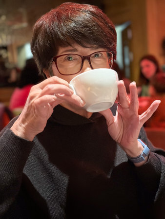 Woman enjoying a warm drink in a cozy cafe. Savoring the moment with quiet reflection and comfort. Break and free time conceptの写真素材