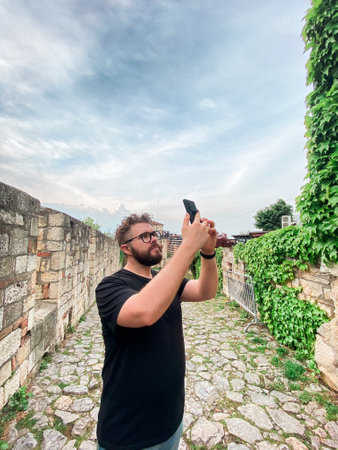 A man takes a photo while standing at a viewpoint in fortress. A tourist with a smartphone cameraの写真素材