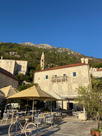 Outdoor cafe in a historic stone building nestled at base of green mountain under a clear blue sky. Tranquil blend of architecture and nature, perfect for a relaxed afternoon.の写真素材