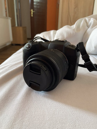 Digital camera rests on a white bed, ready for use, symbolizing creativity and exploration. Relaxed...